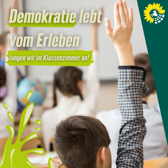 Die Überschrift des Bildes ist: "Deomkratie lebt vom Erleben", darunter steht in beiger Schrift auf hellgrünem Hintergrund "fangen wir im Klassenzimmer an". Das Bild selbst zeigt junge Menschen in einem Klassenzimmer, die die Hand heben und sich so melden. Unten links in der Ecke ist ein großer hellgrüner Farbspritzer und oben rechts in der Ecke ist ein dunkelgrünes Dreieck und das Logo der Grünen Landtagsfraktion.